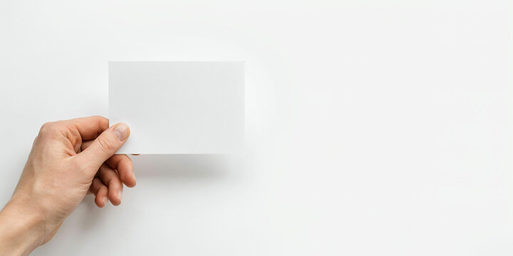 A hand holding a blank white rectangular card against a plain white background, for copy space area