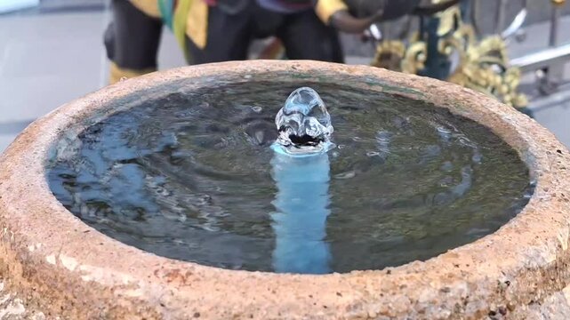 small stone pot fountain bubbling clear water creating circular ripples on surface outdoor garden decoration