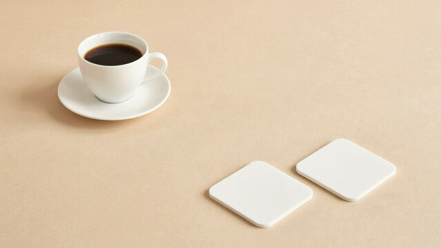 White coffee cup with black coffee and two blank square coasters on a beige background