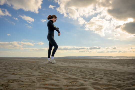 Woman Checking Her Fitness Tracker, Running on the Beach