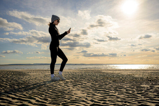 Woman Runner in Winter Sportswear on Sandy Beach