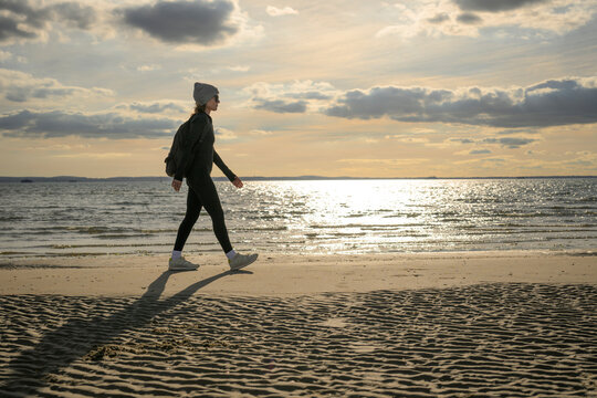 Woman Walking Along Beach at Sunset
