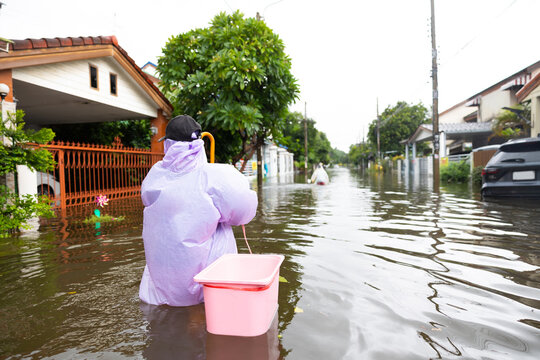 back view, obese woman wearing Raincoat and walking through flood waters to go buy food, lifestyle of Thai people in massive flooding, Severe weather