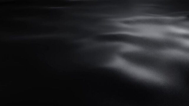 Abstract dark surface with shifting gray ripples and soft highlights in a moody setting