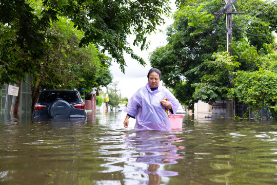 obese woman wearing Raincoat and walking through flood waters to go buy food, lifestyle of Thai people in massive flooding, Severe weather