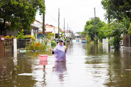 obese woman wearing Raincoat and walking through flood waters to go buy food, lifestyle of Thai people in massive flooding, Severe weather