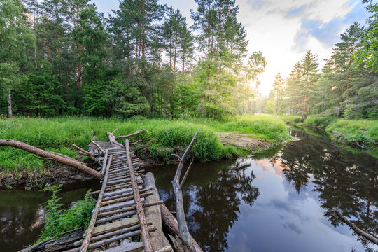 Rustic wooden bridge spans quiet river