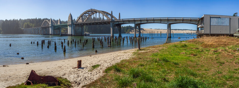 Beautiful wide panoramic view of a historic concrete arch bridge over a river with old wooden piers