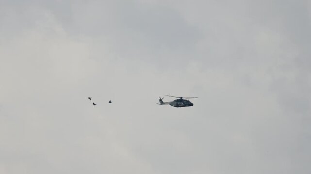 Military transport helicopter dropping paratroopers into the sky