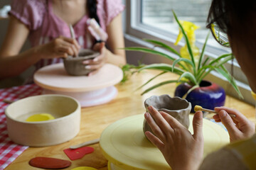 Two People Enjoying Pottery Clay Crafting Workshop Together at Wooden Table by Window in a bright studio workshop © Stella 16