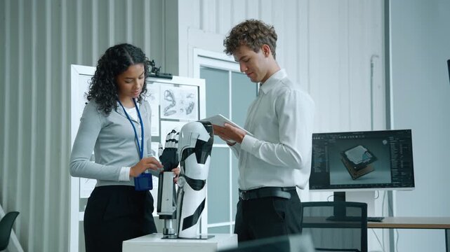 Two engineers examining a humanoid robot prototype while reviewing technical information on a tablet in a modern robotics laboratory, representing research, development, engineering, artificial intell