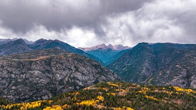 Aerial view of Purgatory Resort featuring rugged mountain peaks, evergreen forests, and autumn foliage under a dramatic cloudy sky in Durango, Colorado, United States.
