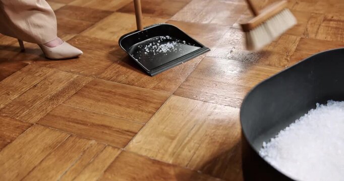 Woman Sweeping Spilled Cat Litter Granules from Wooden Parquet Floor with Broom and Dustpan