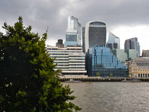 London City Skyline from River Thames - A view of London's financial district skyline featuring modern skyscrapers and historic buildings along the River Thames under a cloudy sky.