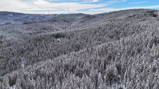 Aerial view of snow-covered forest and wind turbines in the winter landscape of Weststeiermark near Soboth Reservoir, Styria, Austria.