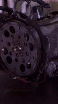 Close-up shot of an auto mechanic using a tool to tighten bolts on a metal engine flywheel during vehicle repair and maintenance.