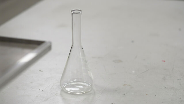 Empty erlenmeyer flask on a white surface keywords: erlenmeyer flask, laboratory, science, empty