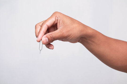 Man holding a sim card ejector tool between fingers isolated on white background