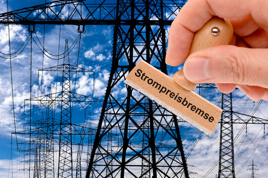 &Uuml;ber vielen Strommasten einer &Uuml;berland-Hochspannungsleitung wird ein Stempel gehalten mit der Aufschrift Strompreisbremse - FOTOMONTAGE