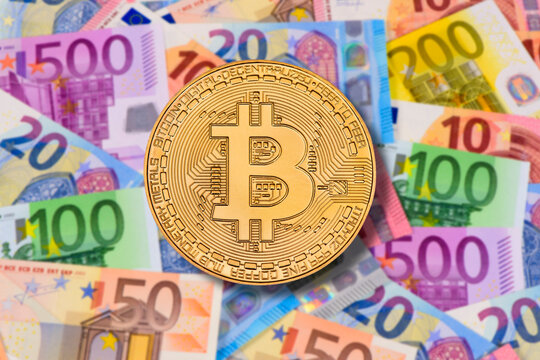 Eine Bitcoin-M&uuml;nze liegt &uuml;ber einem Haufen mit vielen Euroscheinen - FOTOMONTAGE