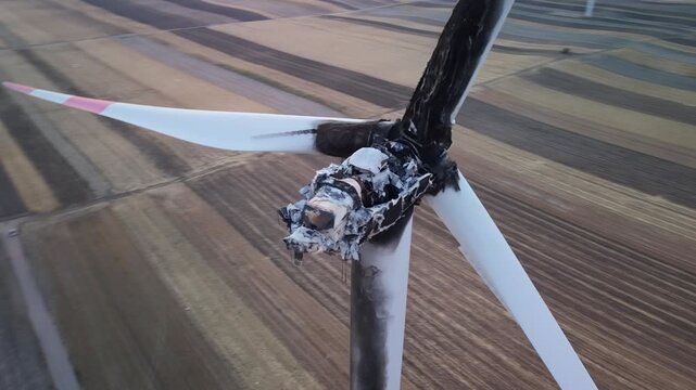 Aerial view of a burnt wind turbine with damaged blades and charred nacelle standing in a vast agricultural field in Vladimirovac, Vojvodina, Serbia.