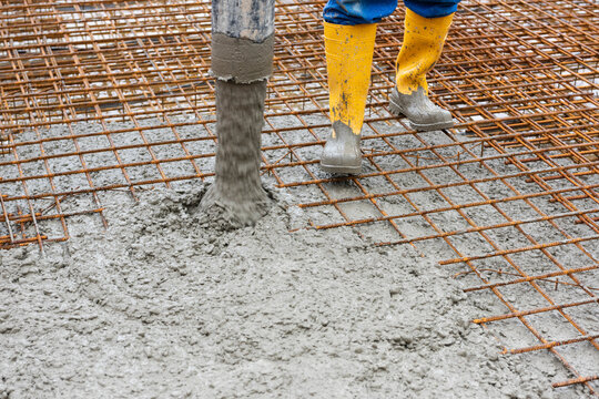 Ein Bauarbeiter betoniert auf Baustahlmatten das Fundament f&uuml;r einen Neubau