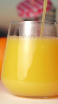 Macro close-up video showing fresh orange juice pouring into a clean transparent glass and forming sparkling fizzy bubbles under bright morning sunlight, perfect for summer refreshment and natural vit