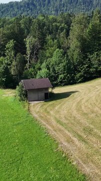Green hills, neat houses in the valley and majestic silhouette of mountains. Summer view of a meadow surrounded by forest. Beautiful landscape, tourism, travel, eco-tourism or retreat