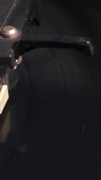 Close-up vertical shot focusing on the edge and surface of a black vinyl record spinning rapidly on a turntable platter.