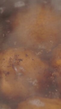 Close-up macro video of whole potatoes boiling in bubbling hot water with spices, creating steam and warm home-cooking visuals.