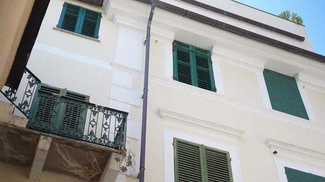 Pan right along an Italian building facade with green shutters