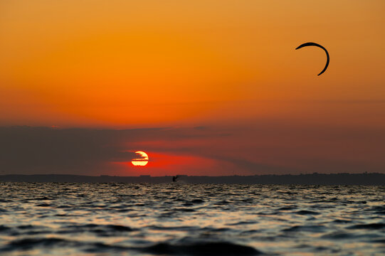 Kitesurfer silhouette during sunset over water