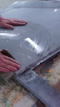 Detailed macro footage of a mechanic manually wet sanding a primed car hood or panel to achieve a perfectly smooth finish.