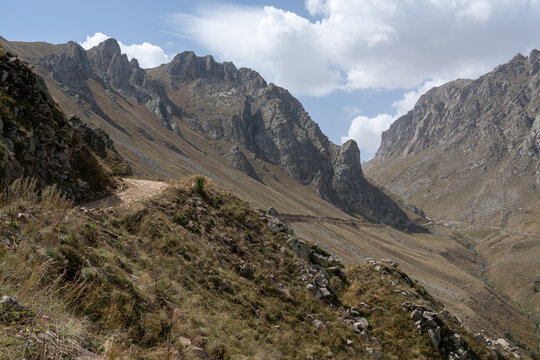 Dramatic Rocky Mountain Valley with Hiking Trail and Jagged Cliffs.