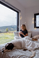 Obraz premium happy woman with dog relaxing in bed at Christmas time