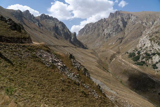 Dramatic Rocky Mountain Valley with Hiking Trail and Jagged Cliffs.