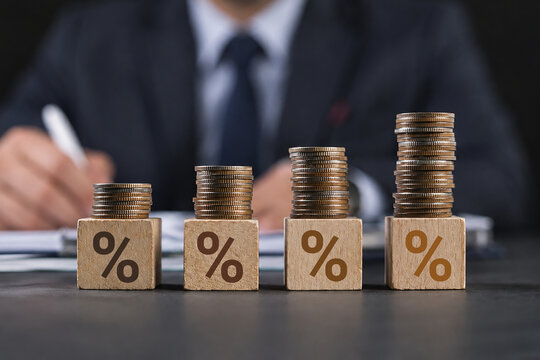 Interest rate finance and mortgage rates. Wooden block with percentage sign on many level of stack of coin. Financial growth, interest rate increase, inflation, sale price and tax rise concept.