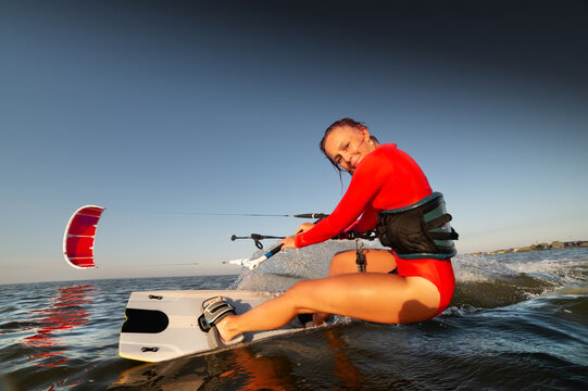 Woman kitesurfing on water with red kite