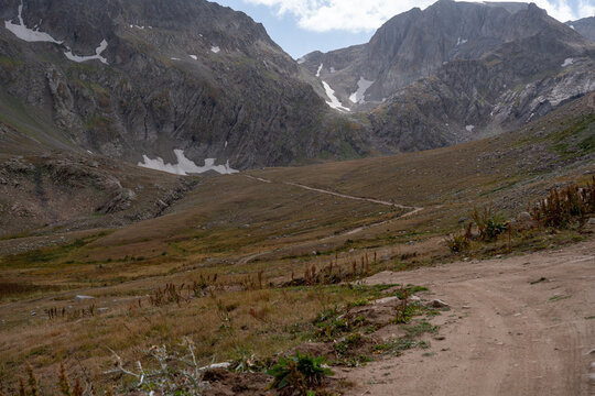Dramatic Rocky Mountain Valley with Hiking Trail and Jagged Cliffs.