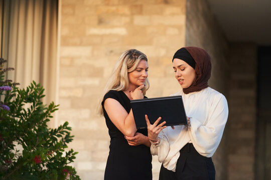Two Business Colleagues Discussing Work on a Laptop During an Outdoor Meeting