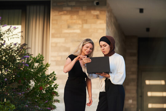 Business Colleagues Collaborating Outdoors With Laptop &mdash; Diverse Female Professionals Discussing Project