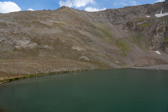 High-Altitude Mountain Lake Surrounded by Rocky Peaks and Snow Patches.