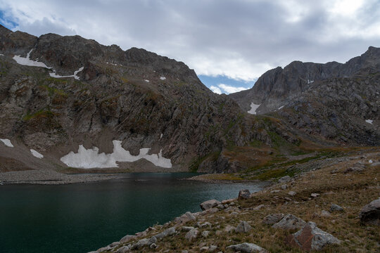 High-Altitude Mountain Lake Surrounded by Rocky Peaks and Snow Patches.