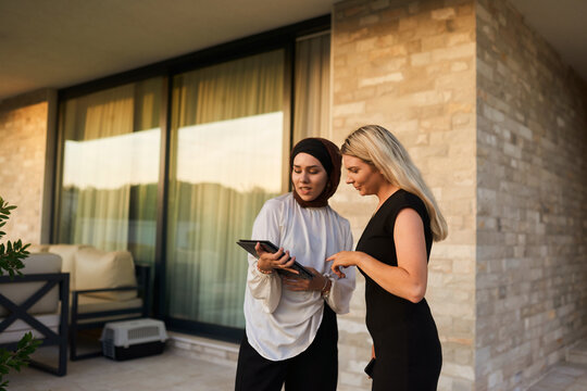 Two Professional Colleagues Discussing Work on a Tablet During an Outdoor Business Meeting