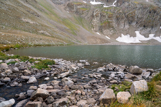 High-Altitude Mountain Lake Surrounded by Rocky Peaks and Snow Patches.