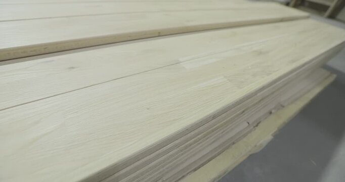 A stack of wooden boards or a furniture panel for woodworking on the floor of a furniture factory workshop. A close-up of a neatly stacked pile of wooden boards and panels in a warehouse.