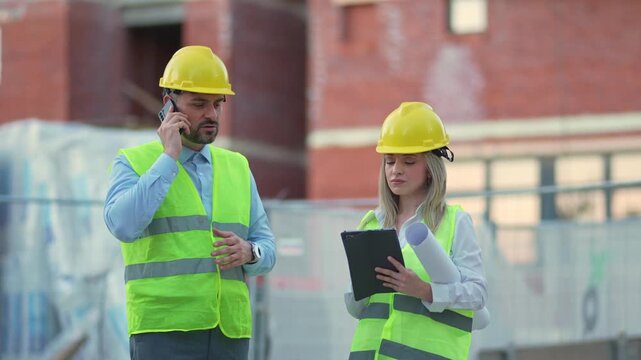 Construction team discusses project updates on site in bright neon vests