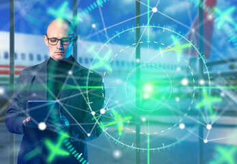 Airport air traffic control, a manager uses a tablet to monitor aircraft movements and coordinate flight routes through a digital radar and aviation tracking system. © Grispb