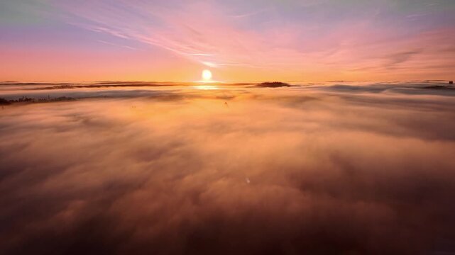 Flying over clouds towards beautiful romantic pink sunrise