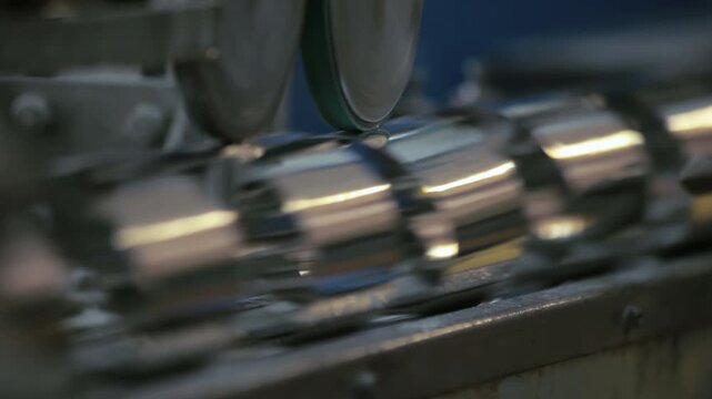 Shiny metal cans moving factory line. Close up canning equipment production.